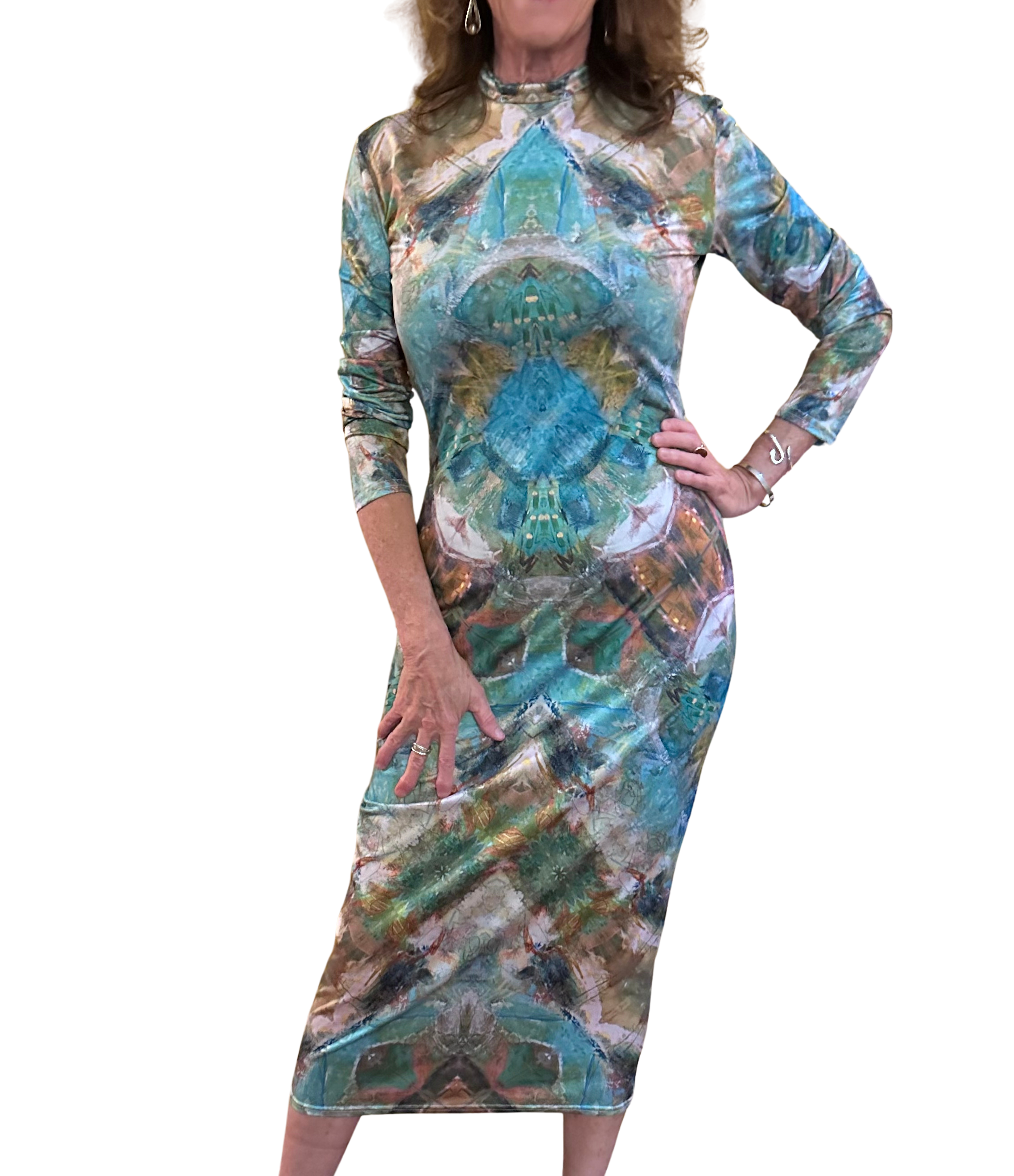 Woman wearing a turquoise and tan abstract patterned dress reminiscent of Middle Eastern patterns. The mid dress is slim fitting with a mock turtleneck and long sleeves.