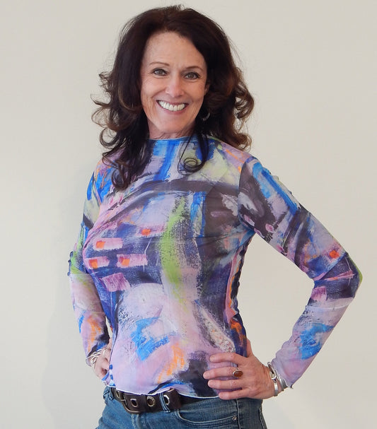 Anita wearing the Raising the Vibration Mesh Top, a vivid abstract painting in royal blue, black, white, pink, lavender and bits of green and orange. 